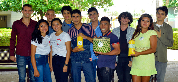 Imagem mostra grupo de pessoas posando para foto. Um dos jovens segura uma cesta verde e amarela.