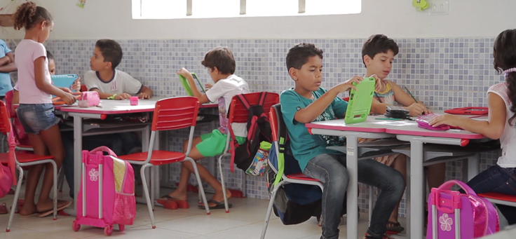 Imagem mostra crianças em sala de aula usando tablet