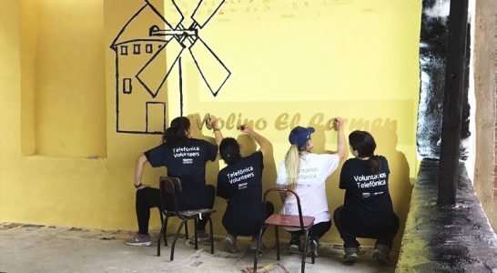 Voluntários pintam parede em Escola Molino de Carmen, no Peru, tem parede pintada com nuvens e arco-íris