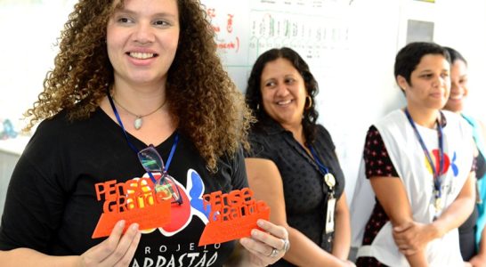 Jovem segura placa com o nome Pense Grande no Lab Maker Arrastão