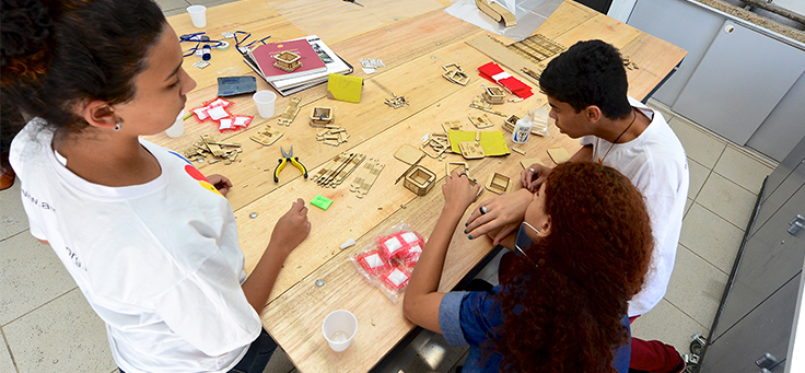 Três jovens em volta de uma mesa no Lab Maker Arrastão