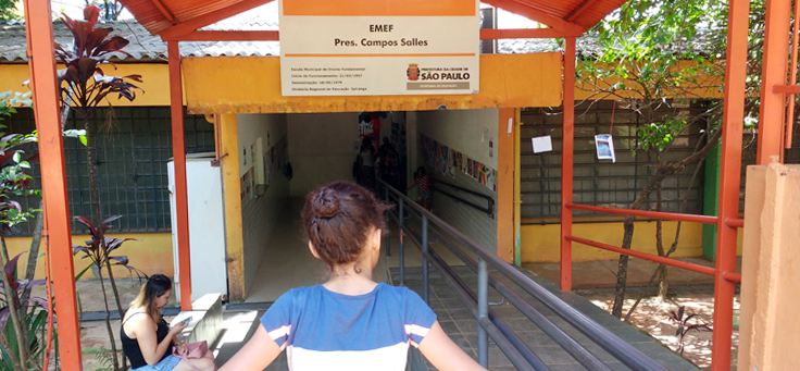 Fachada da escola Campos Salles mostra uma criança olhando para a placa em que está escrito EMEF Campos Salles