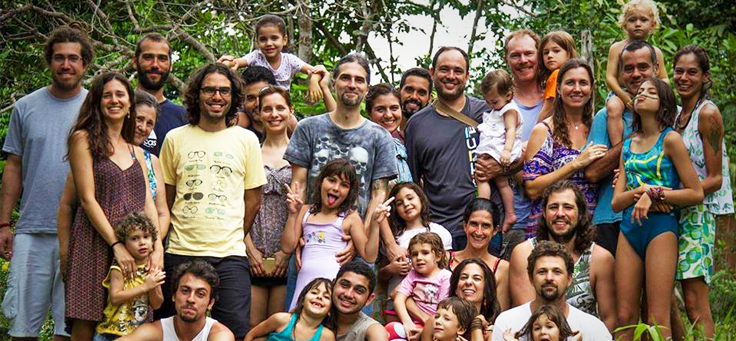 Grupo com cerca de 20 pessoas, de pé e agachadas, entre pais, professores e crianças, com a mata verde como fundo