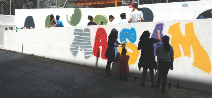 Crianças e adolescente fazem grafite em muro da escola