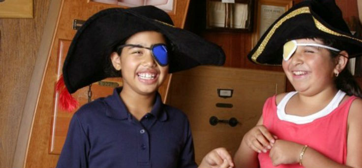 Duas crianças da ONG 826 Valencia se vestem de piratas, com chapeis e tapa-olhos.