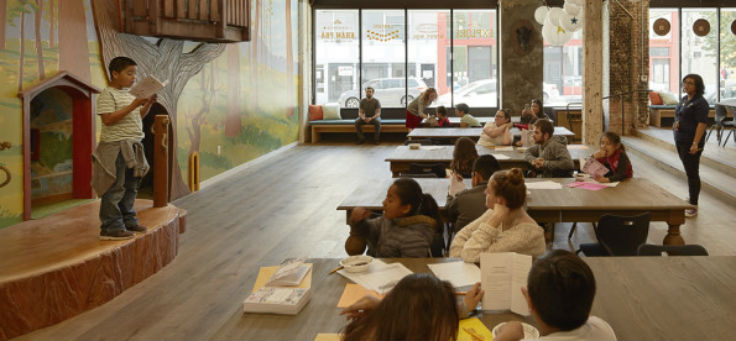 No centro Terdeloin, com motivos de uma casa da árvore no interior, um dos alunos faz leitura do seu livro para as crianças em cima do palco.