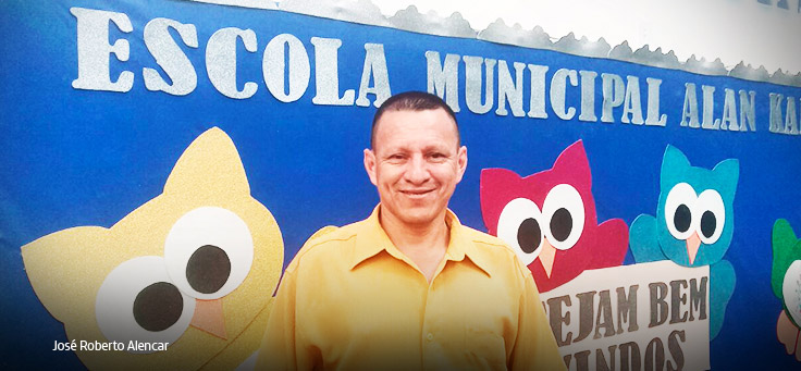 Homem de camisa amarela em frente a muro azul.