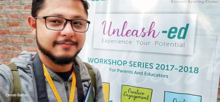 Rapaz de óculos sorri em frente a banner onde se lê “Unleash-Ed – Explore your Potential”
