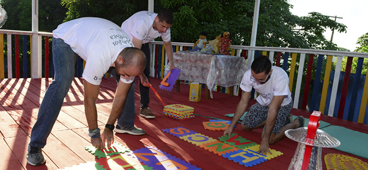 Voluntários pintam chão da escola durante o Vacaciones Solidárias em Manaus
