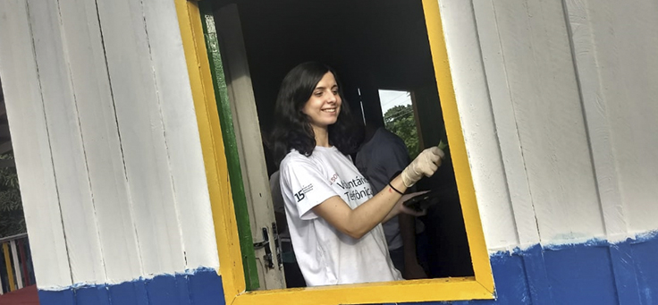 Voluntária pinta janela da escola durante o Vacaciones Solidárias em Manaus