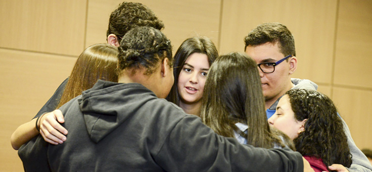 Na imagem, grupo de jovens do programa Pense Grande se abraça coletivamente, formando um círculo