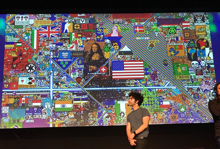 Palestrante posa em frente a quadro que reúne diversas ilustrações com referências culturais, como Monalisa e bandeiras de países como EUA