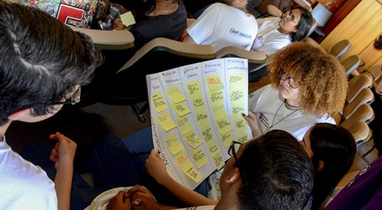 Trainees olham para cartaz com post-its amarelos