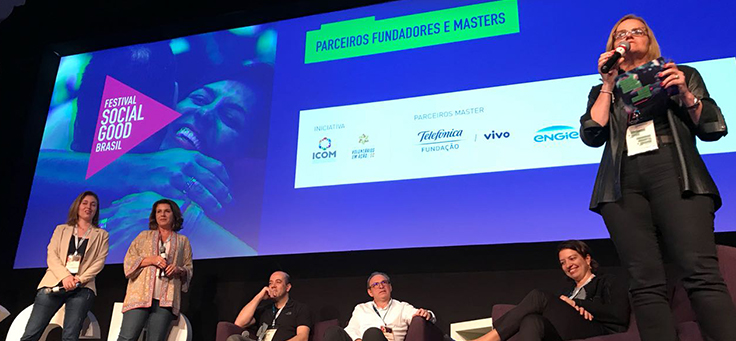 Três palestrantes estão em pé e outros três sentados no palco do festival Social Good Brasil
