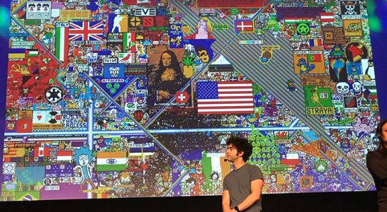 Palestrante posa em frente a quadro que reúne diversas ilustrações com referências culturais, como Monalisa e bandeiras de países como EUA