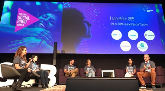 Seis palestrantes dividem palco do festival Social Good Brasil. Eles estão sentados em sofás e poltronas
