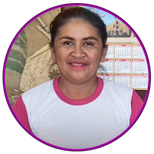 A professora Luciana Pascoal Araújo está com os cabelos presos e sorri para foto. Ela usa uma camiseta branca com mangas e gola rosa.