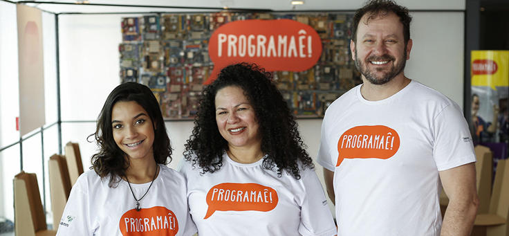 Três facilitadores do Programaê posam com camisetas do programa em estande do Educação 360