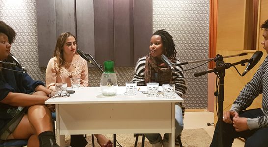 Quatro jovens conversam dentro de um estúdio de gravação