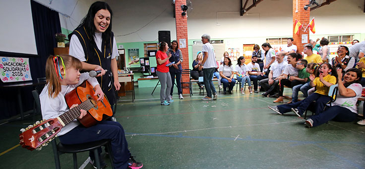 Aluna da Escola Primavera toca violão durante apresentação para voluntários.
