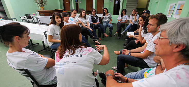 Imagens mostra voluntários sentados em roda na Escola Primavera