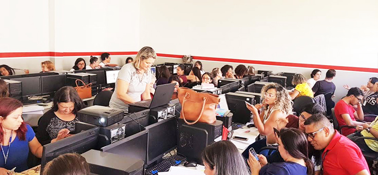 Professores estão sentados em grupos em torno de computadores durante formação continuada da Fundação Telefônica Vivo em parceria com a Undime.
