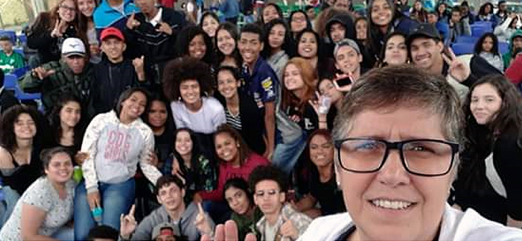 Alunos e professores da Escola Estadual Professor Joaquim Luiz de Brito posam em festival contra homofobia. Um homem de óculos aparece em primeiro plano com o grupo de alunos atrás dele.
