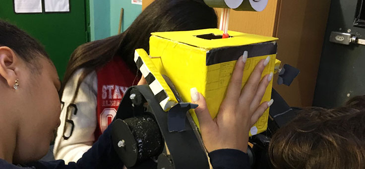 Alunos estão colando a cabeça de um robô feito de sucata em aula da professora Débora Garofalo, finalista do Nobel da Educação.