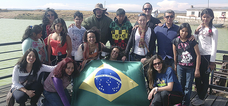 Um grupo de brasileiros e estrangeiros posa para a foto com a bandeira do Brasil. Matéria debate inclusão de refugiados
