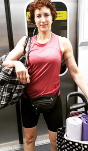 Sophia Bisilliat, uma das representantes de mulheres poderosas, está com uma bolsa grande pendurada no ombro e um carrinho com tapetes de ioga em um vagão de metrô em São Paulo.