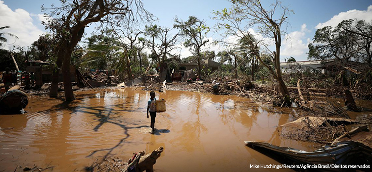 Imagem mostra região de Moçambique alagada devido ao ciclone Idai. Uma criança atravessa água barrenta segurando um cesto