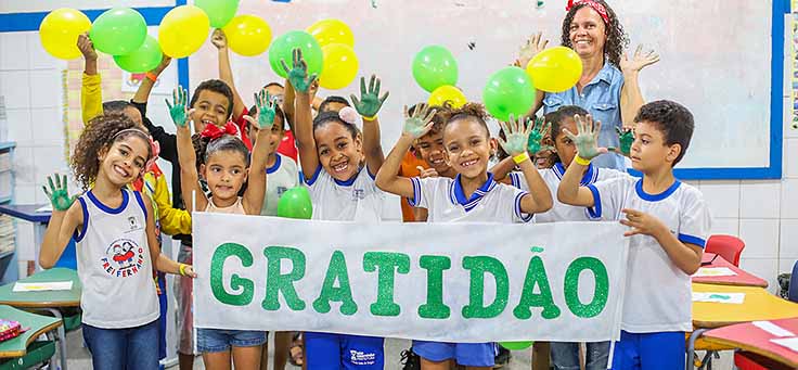 Alunos da Escola Municipal de Ensino Fundamental Frei Fernando seguram faixa com a palavra gratidão ao final do programa de voluntariado Vacaciones Solidárias.