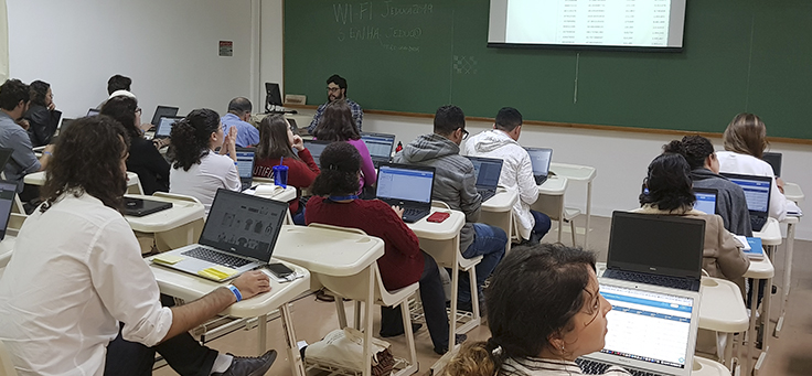 Cerca de 30 pessoas estão sentadas em carteiras, usando notebooks e olhando para uma projeção durante uma das oficinas do Jeduca 2019.