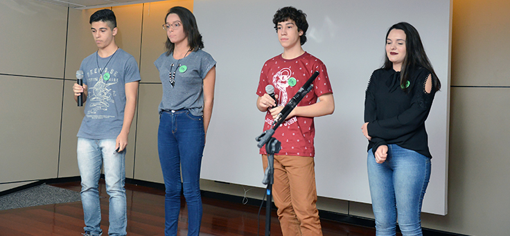 Grupo de quatro estudantes se apresenta durante o Demoday. Dois deles estão com o microfone nas mãos