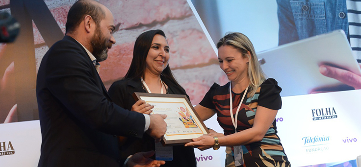 Imagem mostra participantes do grupo Arteduca recebendo prêmio de Americo Mattar, Diretor-Presidente da Fundação Telefônica Vivo