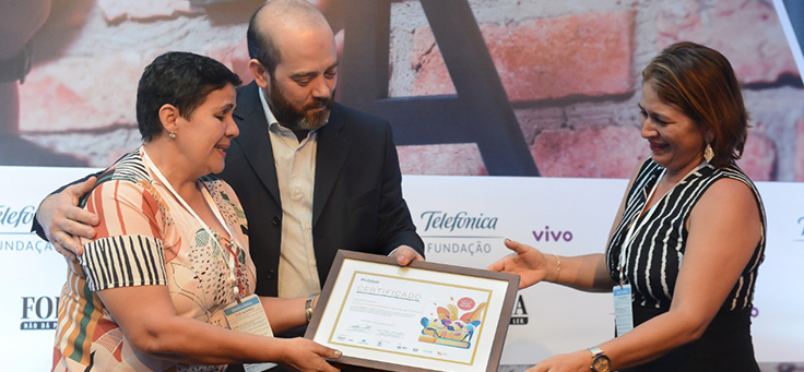 Imagem mostra participantes do grupo Nenhum a Menos recebendo prêmio de Americo Mattar, Diretor-Presidente da Fundação Telefônica Vivo