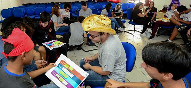 Imagem mostra pessoas realizando uma atividade em grupo dentro de uma sala