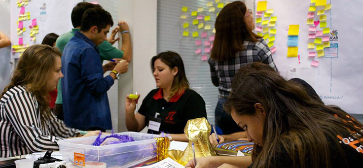 Na imagem estudantes da Academia Educar, que contribui para a formação de jovens, estão montando quadros com ajudas de materiais como post-its.