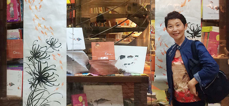 A escritora Lúcia Hiratsuka posa para foto em frente à vitrine de uma livraria