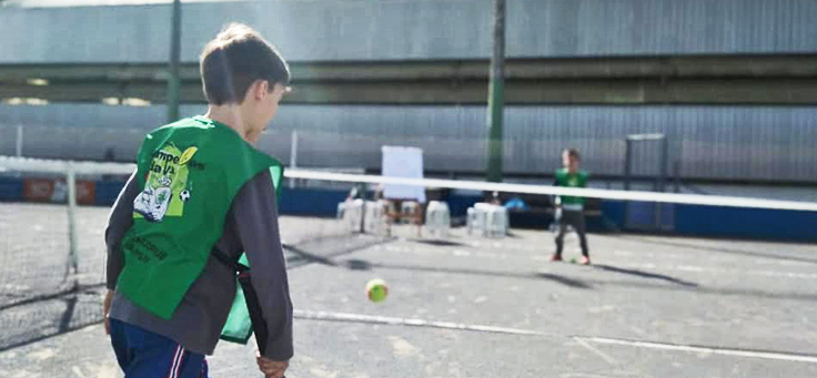 Imagem mostra duas crianças jogando tênis em uma quadra