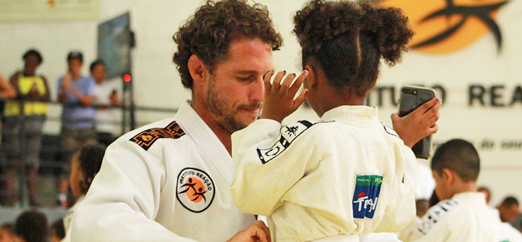 Imagem mostra o ex-judoca Flávio Canto e uma criança de costas usando quimonos