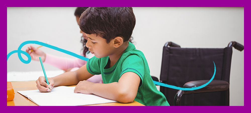 Aluno em cadeira de roda está escrevendo em um caderno na sala de aula para ilustrar a importância de promover uma educação inclusiva. Ele é um menino com menos de 10 anos de idade e tem cabelo curto e preto.