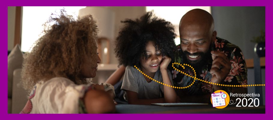 Imagem mostra uma família negra olhando para a tela de um tablet que está apoiado no sofá e sorrindo