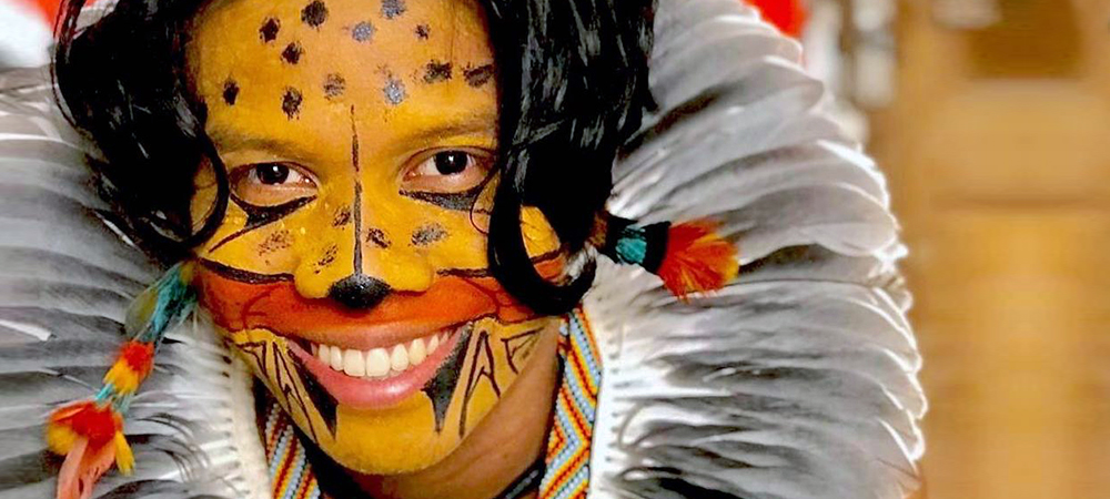 Tukumã Pataxó se destaca pelo ativismo indígena e aparece com pintura no rosto que se assemelha a uma onça, além de um cocar na cabeça, com penas em tons de cinza.