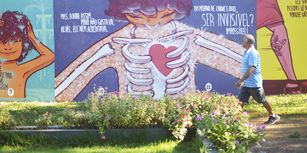 A imagem mostra detalhes do muro grafitado com o livro Menino Invísivel