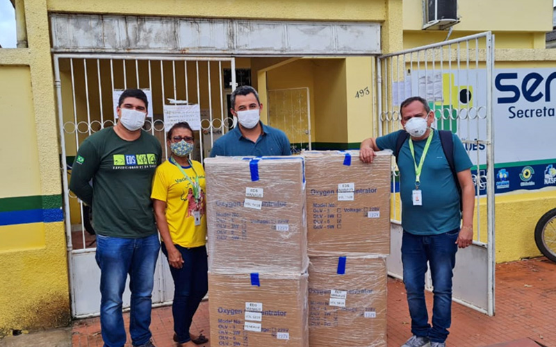 Imagem mostra um grupo usando máscaras de proteção e posando para a foto atrás de várias caixas de papelão com equipamentos médicos doados pela Fundação Telefônica Vivo em ação emergencial de apoio ao Amazonas