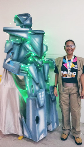A professora Keila posa para foto ao lado de um robô construído com lixo eletrônico