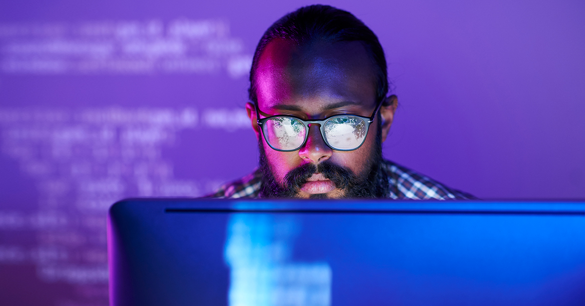 Imagem de um homem de óculos olhando para o computador.