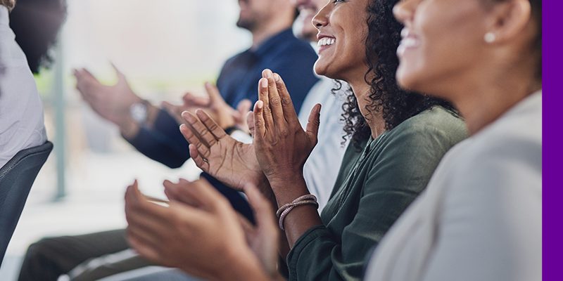 Imagem mostra pessoas sorrindo e aplaudindo a entrega do prêmio