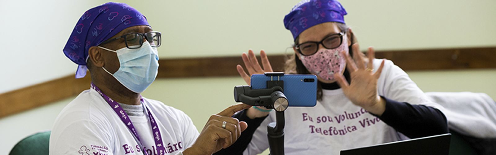 dois colaboradores, usando a camiseta do projeto, participam de atividade on-line do Dia dos Voluntários Telefônica Vivo